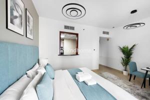 a white and blue bedroom with a bed and a table at Luxury Unit Located in Icon Tower, JLT in Dubai +3 photos