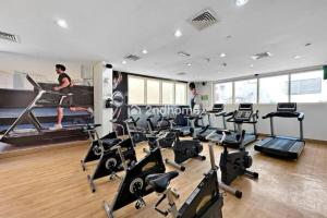 a gym with cardio equipment and two men in the background at Luxury Unit Located in Icon Tower, JLT in Dubai