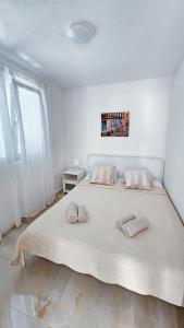 a white bedroom with a large bed with two pillows at Apartments Šolta in Rogač