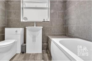 a bathroom with a tub and a toilet and a sink at OnSiteStays - Large 3 bedroom, 2 bathroom, driveway, Garden, Sleeps 6 Comfortably in Bexleyheath +11 photos