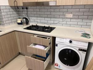 a kitchen with a stove and a washing machine at condo for 4 pax at bayuemas klang in Klang