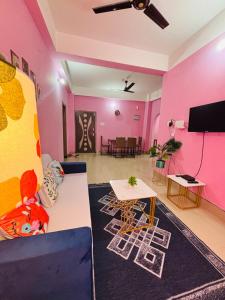 グワーハーティーにあるDreamy Den Homestayのピンクの壁のリビングルーム(ソファ付)