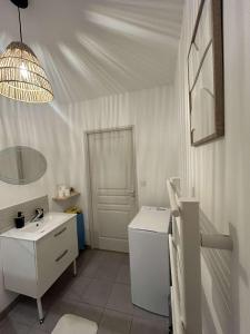a white bathroom with a sink and a mirror at Appartement Centre ville in Vierzon