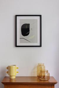 a picture on a white wall with a wooden table at Guersant - Maison cosy 6PAX proche Etoile in Paris