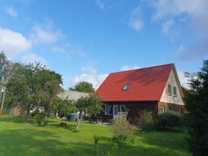 a house with a red roof on a green field at Kāpas in Jūrkalne