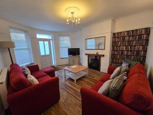 a living room with two red couches and a table at Beach Flat in Birchington