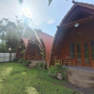 a wooden house with a lawn in front of it at WArDiTa Paddy Lodge in Labuhanamuk