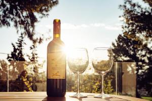 a bottle of wine and two wine glasses on a table at Jasmin House - Sea view - In town in Skála Oropoú