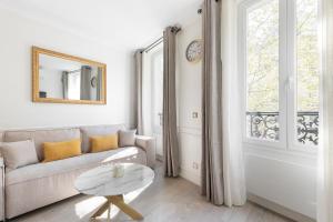 a white living room with a couch and a table at Pick A Flat's Apartments in Batignolles - Rue Gauthey in Paris
