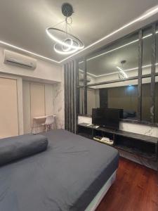 a bedroom with a large bed and a television at Apartment Orchard Tanglin Pakuwon Mall in Surabaya