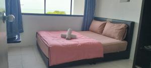 - un petit lit dans une chambre avec une couverture rose dans l'établissement Sariayang resort, à Pantai Cenang