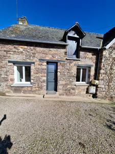 a stone house with a blue door and windows at La petite maison dans la prairie in Plélan-le-Grand
