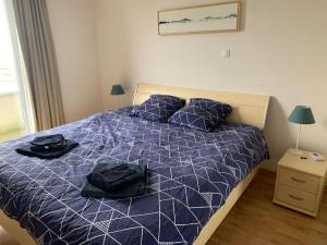 a bedroom with a bed with blue comforter and pillows at Vue Mer, Golfe et Dunes- Résidence Dunes du Golfe in Wimereux