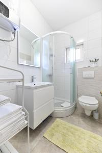 a white bathroom with a sink and a toilet at Apartments Martom 1 in Seline +58 photos