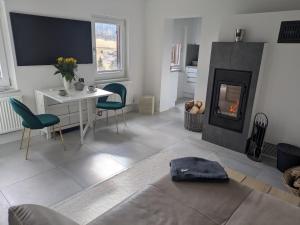 a living room with a fireplace and a table and chairs at Haus am Waldrand in Großbreitenbach