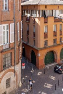 a person riding a bike down a street next to a building at Le Concon Rose - Hyperb centre - Clim - WIFI & Netflix in Toulouse