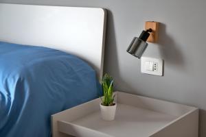 a white nightstand with a plant on it next to a bed at La caldera in San Giuseppe Vesuviano