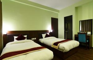 a hotel room with two beds and a desk at Hotel Harmony in Kathmandu