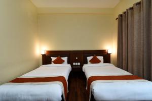 two beds in a hotel room with white and red pillows at Hotel Harmony in Kathmandu