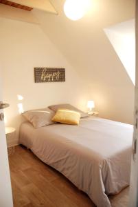 ein Schlafzimmer mit einem weißen Bett und einem gelben Kissen in der Unterkunft El pisito Quimperois duplex 2 chambres coeur de ville in Quimper