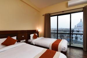 Una habitación de hotel con dos camas y una gran ventana. en Hotel Harmony, en Katmandú