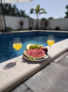 two glasses of wine and a plate of fruit next to a pool at Villa Lauvi, Free Fiat 500 Cabriolet, Scooters , PS5 in Kaštela