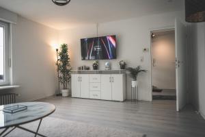 a white living room with a tv on the wall at Maisonette Apartment mit Panorama Terrasse in Kaiserslautern WeHome Premium in Kaiserslautern