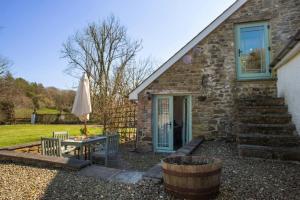 a stone house with a table and an umbrella at Orchid Cottage Aberporth in Aberporth