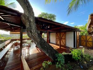 a house with a tree leaning over the deck at Pousada Naiepe in Fernando de Noronha