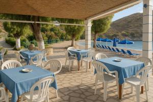 a patio with tables and chairs and a beach at KALIVAKI in Georgioupolis