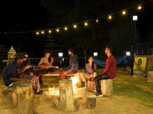 a group of people sitting around a fire at night at The Hosteller Bir in Bīr