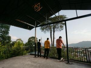 three men standing on a balcony looking at the water at The Hosteller Bir in Bīr +15 photos
