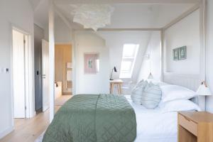 een witte slaapkamer met een groot bed met een groene deken bij Tide's Watch in Beadnell