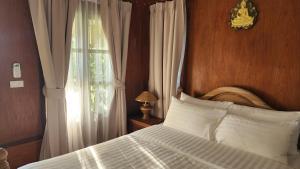 a bedroom with a bed with white pillows and a window at Fa Sunset Cottage in Hinkong