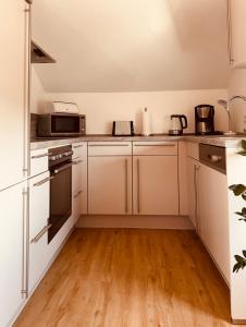 Una cocina con electrodomésticos blancos y suelo de madera. en Ruhrtalblick Apartments - Auszeit mit Ausblick, en Meschede