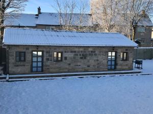 a small stone house with snow on the ground at The Owl Stony Snug in Carstairs Junction +2 photos