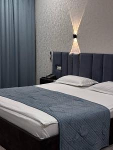 a bedroom with a large bed with a blue headboard at JETISY COMPLEX in Taraz