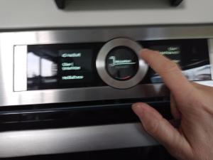 a hand is pushing a knob on a microwave at Vakantiewoning met serre en airconditioning in Tzummarum