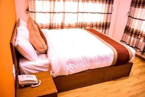un letto in una camera con telefono su un tavolo di Kathmandu Peace Hotel a Kathmandu