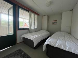 two beds in a small room with a window at Kyläkaupan Motelli in Räyskälä