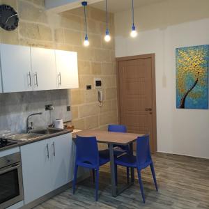 a kitchen with a wooden table and blue chairs at Senglea Apartments in Senglea