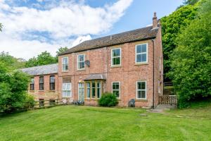 una vecchia casa in mattoni con un ampio cortile di Cote Ghyll Mill Holiday Apartments a Osmotherley