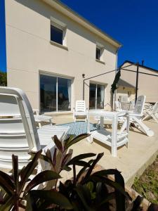 a patio with white lounge chairs and a building at La P'tite Huguette in Port-en-Bessin-Huppain