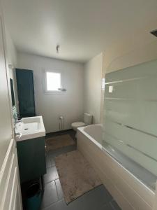 a bathroom with a tub and a toilet and a sink at La P'tite Huguette in Port-en-Bessin-Huppain +2 photos