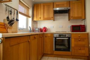 a kitchen with wooden cabinets and a red microwave at Cuckoo Springs Cottage Aberporth in Aberporth