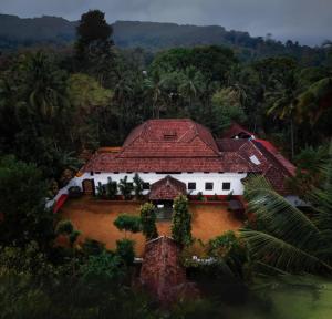 an aerial view of a house with a red roof at SaffronStays Amaya - 5BR 300-year-old Kerala-style heritage home near Kannur Airport in Irikkūr