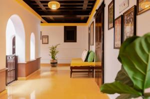 a hallway with a couch in a building at SaffronStays Amaya - 5BR 300-year-old Kerala-style heritage home near Kannur Airport in Irikkūr