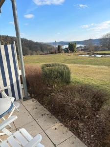 a pair of white chairs and a table and a field at Kleine FeWo mit Seeblick in Spalt