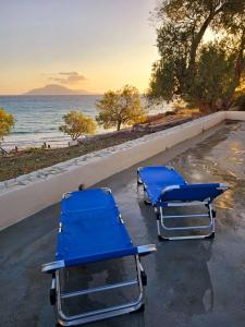 two blue beach chairs sitting next to the ocean at Aether Beach House in Foinikion +6 photos