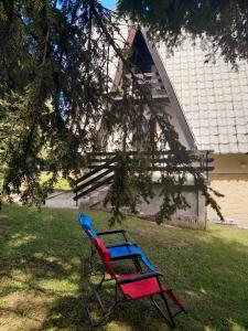 una panchina rossa e blu davanti a una casa di Pine tree cottage a Zlatibor
